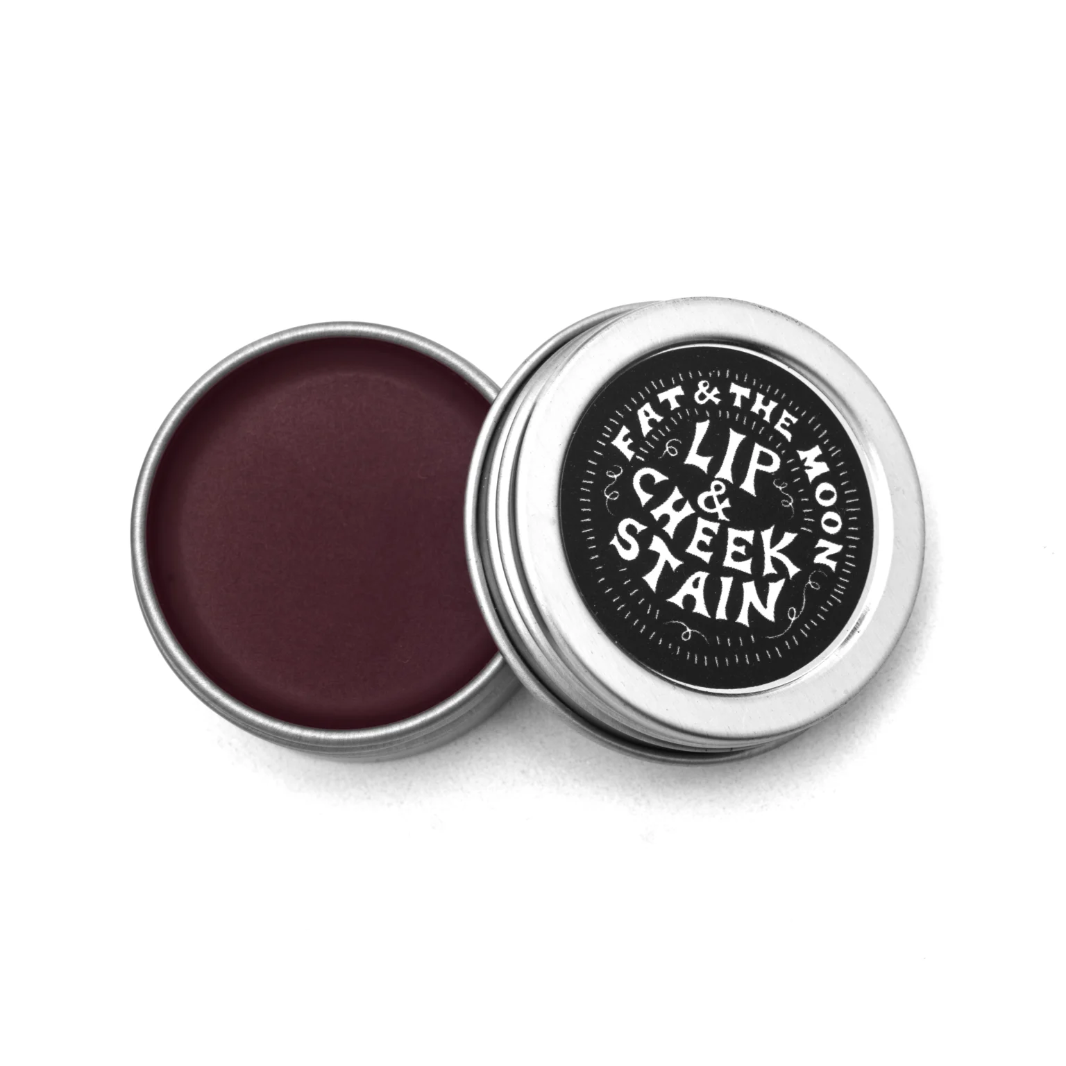 Open tin of Fat and the Moon lip and cheek stain in deep berry color on a white background